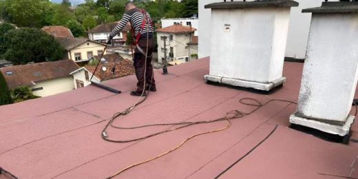 Le patron pose l'étanchéité sur un toit plat rose avec outils, deux cheminées, vue Le Cannet.