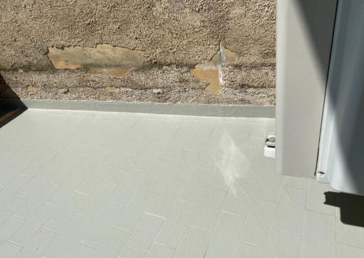 Mur béton patiné, peinture écaillée, sol carrelé clair, expertise locale zéro sinistre, lumière naturelle.