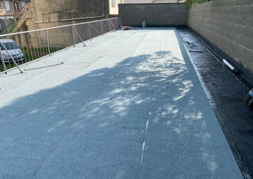 Toit plat, membrane étanche posée par patron expert, zéro sinistre, ombres d'arbres sur surface.