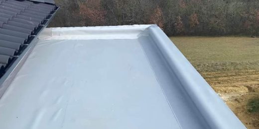 Toit plat gris clair étanchéité Rina, bords surélevés, vue champs, réalisé sans sous-traitance.